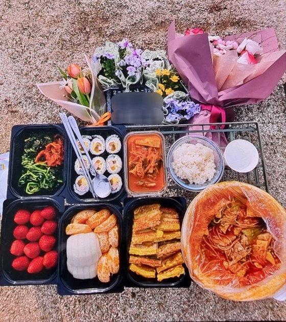 Food and flowers are laid out to commemorate Yoo Ye-na (pseudonym), a woman who took her own life after she aged out of the foster care system, on April 10. [JOONGANG ILBO]