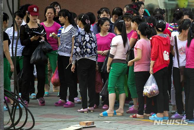 [훈춘=AP/뉴시스]북중 접경 지역인 단둥에서 북한인 근로자들이 이례적으로 시내 관광에 나섰다고 아사히신문이 9일 보도했다. 사진은 지난 2017년 9월2일 홍차오즈이 의류공장의 북한 노동자들이 중국 북동부 지린성 훈춘시의 한 시장에서 쇼핑을 한 후 인원수를 파악하기 위해 모여있는 모습. 2024.05.09.