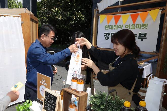 현대위아의 한 직원이 9일 경남 창원 현대위아 본사에서 열린 ‘이음마켓’에서 지역 농가에서 만든 제품을 사고 있다.(사진=현대위아)