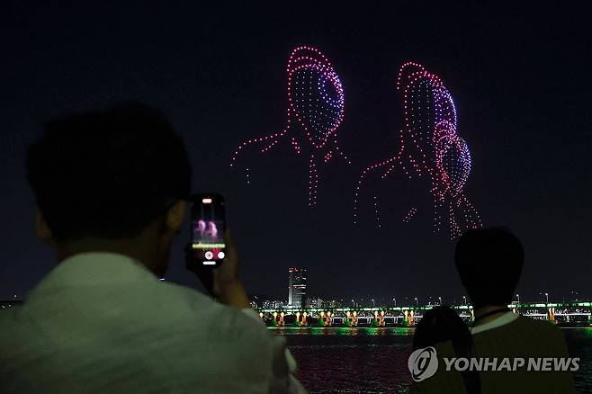 잠실한강공원에서 펼쳐지는 드론 라이트쇼 (서울=연합뉴스) 신현우 기자 = 27일 오후 서울 송파구 잠실한강공원을 찾은 시민이 '인조이 올 댓 서울(Enjoy All that Seoul)'을 주제로 열린 한강 드론 라이트쇼를 스마트폰으로 촬영하고 있다.
    서울시는 이날부터 6월 1일까지 총 다섯 차례에 걸쳐 잠실한강공원과 광진구 뚝섬한강공원에서 한강 드론 라이트쇼를 선보인다. 하반기 공연은 9∼10월 중 총 5회 열린다. 2024.4.27 nowwego@yna.co.kr