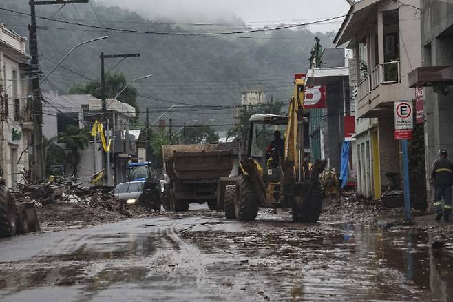 브라질 히우그란지두술주 지역의 한 마을에서 작업자들이 홍수로 더러워진 거리를 청소하고 있다. (사진=AFP)