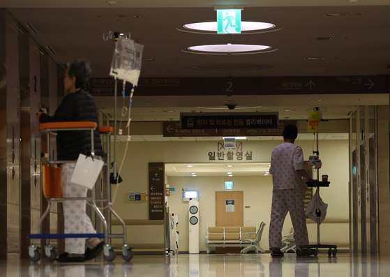 Patients walk down a darkened corridor in an unspecified major hospital in Seoul on Sunday. [YONHAP]