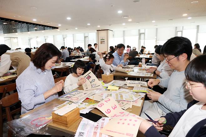 대우건설 임직원과 가족들이 지난 11일 서울 중구 대우건설 본사에서 점자 KIT를 배부 받아 교구를 제작하고 있다. [대우건설]