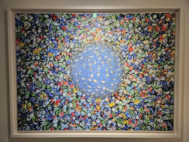 ‘블루’(설치)&nbsp;&&nbsp;‘블루’(사진).&nbsp;&nbsp;숟가락을 이어붙여 만든 반구&nbsp;형태는 ‘이상적인 지구’이고, 주변 음료 캔들은 인간 탐욕이 부른 환경재난이다.&nbsp;