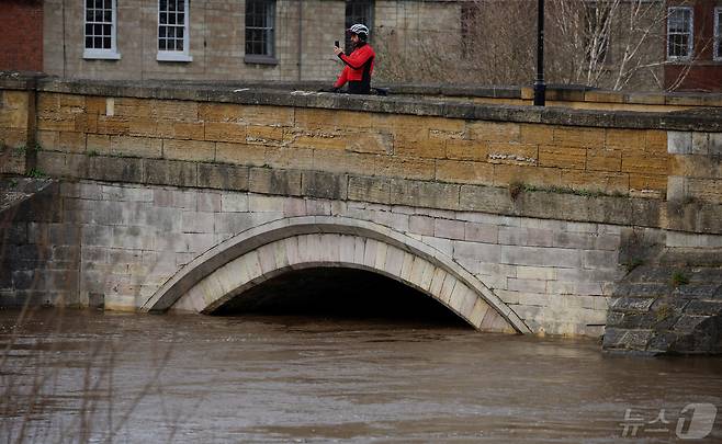 영국 와프강에서 한 사이클 선수가 수위 상승으로 통행이 통제된 다리 위에서 사진을 찍고 있다. 2024.01.24/ ⓒ 로이터=뉴스1 ⓒ News1 권진영 기자