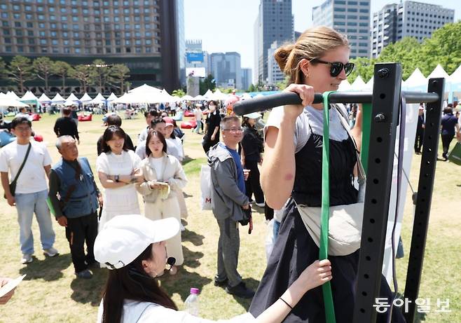 14일 서울 중구 서울시청 앞 서울광장에서 열린 ‘2024 서울 헬스쇼’에서 외국인 관광객들이 풀업 373 부스에서 턱걸이 체험을 하고 있다. 최혁중 기자 sajinman@donga.com