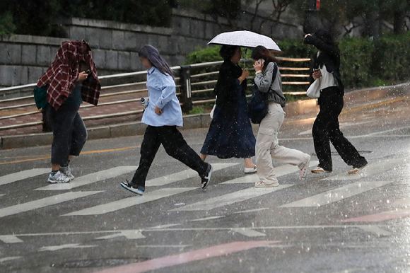 서울 명동성당 인근 거리에서 우산을 챙기지 못 한 시민들이 황급히 이동하고 있다. [사진=뉴시스]