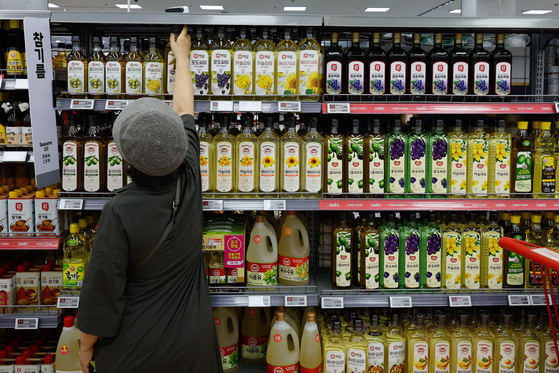 A customer selects from different cooking oils displayed at a supermarket in Seoul on Thursday. [NEWS1]