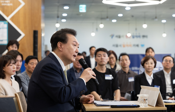 President Yoon Suk Yeol, left, speaks during a public livelihood debate on labor issues, the 25th town hall session of its kind, at an employment and welfare center in central Seoul on Friday. [PRESIDENTIAL OFFICE]
