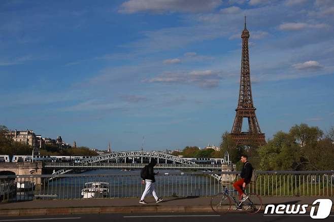 10일(현지시간) 파리 센강에서 한 보행자가 에펠탑을 배경으로 자전거를 타고 이동하고 있다. 2024.04.11 ⓒ AFP=뉴스1 ⓒ News1 조소영 기자