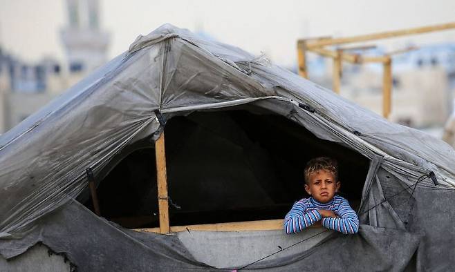 13일(현지시각) 팔레스타인 가자 남부 라파흐의 난민 캠프에서 한 소년이 텐트 밖을 바라보고 있다. 라파흐/AFP 연합뉴스