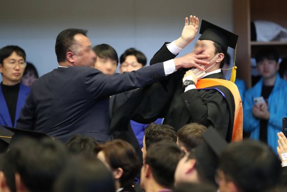 한국과학기술원(KAIST)에서 열린 2024년 학위수여식에서 윤석열 대통령에게 항의하던 한 졸업생이 경호원들로부터 제지를 당하고 있다. 뉴스1