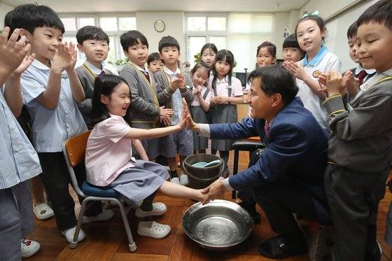 스승의 날을 하루 앞둔 14일 오전 대구 동구 봉무동 영신초등학교에서 열린 '사랑의 세족식'에 참여한 1학년 담임 교사가 정성을 다해 학생들의 발을 씻어주며 즐거운 학교생활을 다짐하는 하이파이브를 나누고 있다. 뉴스1