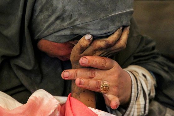 9일 가자지구에서 이스라엘의 공습으로 사망한 아들의 손을 잡은 팔레스타인 여성의 모습. 로이터=연합뉴스