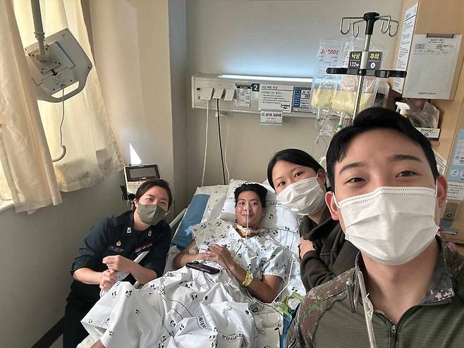 글 작성자 A씨가 공개한 사진. 사연의 주인공인 B씨가 병원 침실에 누워있고, 동료들이 그 주변을 둘러싸고 서 있다. /페이스북