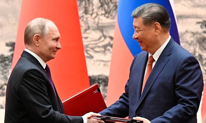 블라디미르 푸틴(왼쪽) 러시아 대통령과 시진핑 중국 국가 주석이 16일 중국 베이징에서 회담 중 서명한 문서를 교환하면서 악수하고 있다. AP뉴시스