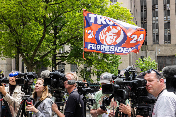 지난 14일(현지시간) 도널드 트럼프 전 미국 대통령이 성추문 입막음 사건 관련 재판을 받고 있는 뉴욕시 맨해튼법원 바깥에서 취재진이 대기하는 가운데 트럼프 지지 깃발이 펄럭이고 있다. AFP연합뉴스