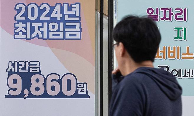 서울 마포구 서부고용복지플러스센터에 놓인 2024년도 최저임금 안내문 앞으로 한 시민이 지나고 있다. 뉴스1