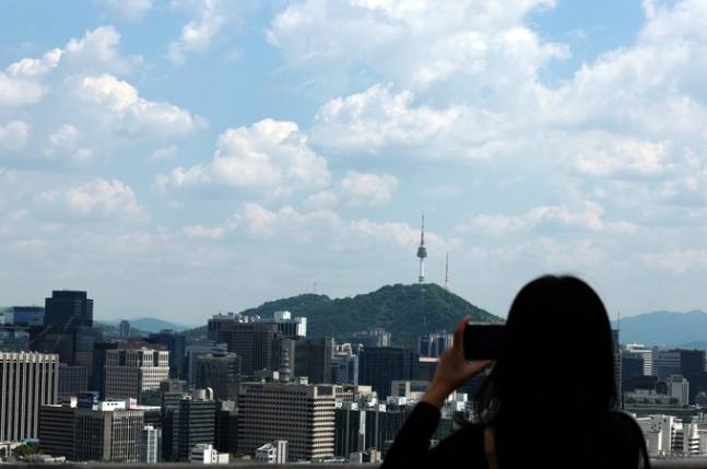 맑은 날씨를 보인 지난 8일 오후 서울 종로구 전망대를 찾은 한 시민이 풍경을 촬영하고 있다. 뉴시스