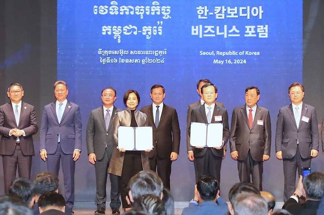 Woori Bank CEO Cho Byung-kyu (front right) and National Bank of Cambodia Governor Chea Serey (front left) pose for a photo during a ceremony at the Korea Chamber of Commerce and Industry in central Seoul, Thursday. (Woori Bank)