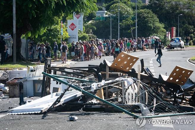 식량 구입을 위해 줄 서 있는 누벨칼레도니 시민들 (누메아[누벨칼레도니] AFP=연합뉴스) 태평양내 프랑스령 누벨칼레도니 수도 누메아에서 2024년 5월 18일(현지시간) 시민들이 소요사태로 불에 탄 물건들이 놓인 도로 변 슈퍼마켓에서 식량을 사려고 길게 줄을 서 있다.