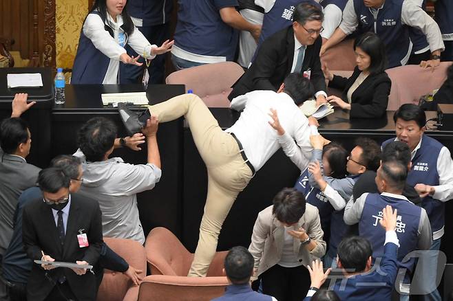 17일(현지시간) 대만 여당 민진당 의원이 타이베이 의회에서 개혁법안 표결 중 의장석으로 뛰어 오르고 있다. 2024.05.17 ⓒ AFP=뉴스1 ⓒ News1 우동명 기자