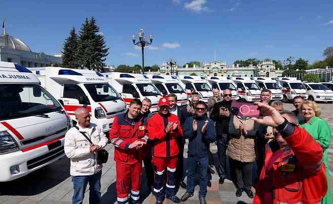 지난 15일 오전(현지 시각) 우크라이나 수도 키이우의 대통령 관저 앞에서 대한적십자사가 보낸 구급차 (현대·기아차 제작) 40대의 전달식이 열렸다. 전달식이 끝난 후 구급대원들이 앰뷸런스를 배경으로 사진을 찍고 있다. / 오종찬 기자