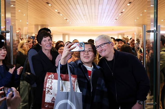 팀 쿡 애플 최고경영자(CEO)가 지난 3월 중국 상하이 애플스토어 개장식 행사에 참석해 현지 고객과 셀카를 찍고 있다./연합뉴스