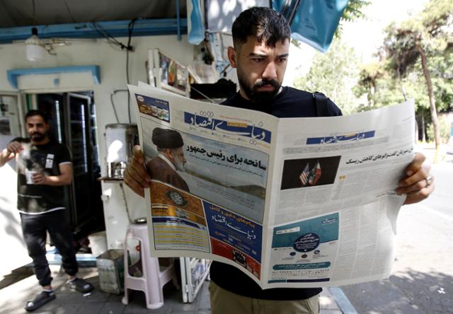 20일 이란 테헤란의 한 거리에서 한 시민이 에브라힘 라이시 대통령이 탄 헬기 추락 소식을 전한 지역 신문을 읽고 있다. 테헤란=EPA 연합뉴스