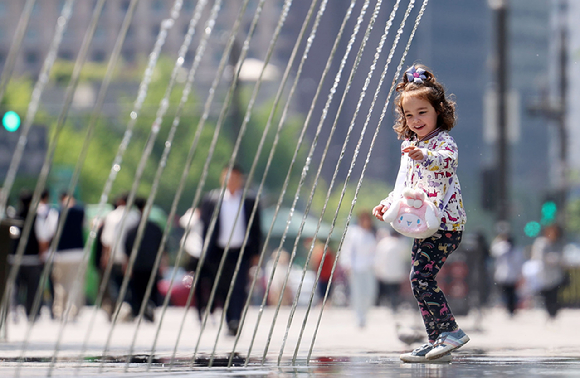 서울 종로구 광화문광장 터널 분수대를 찾은 한 외국인 어린이가 환하게 웃고 있다. [사진=뉴시스]