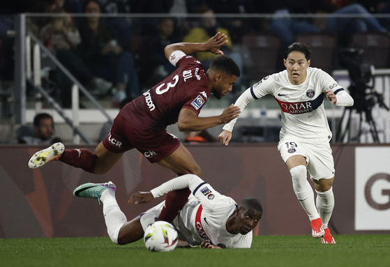Paris Saint-Germain's Lee Kang-in, right, and teammate Nordi Mukiele in action with Metz's Matthieu Udol at the Stade Saint-Symphorien in Metz, France on Sunday. [REUTERS/YONHAP]