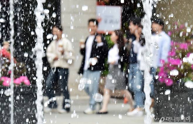 서울 광화문 광장을 찾은 시민들이 한손에 아이스커피를 들고 분수대 주변을 거닐고 있다.