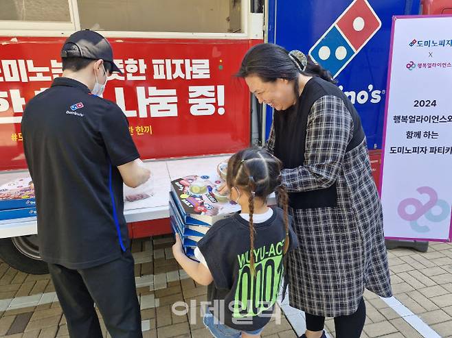 행복얼라이언스가 지난 13일 도미노피자와 함께 피자 나눔 푸드트럭 ‘도미노피자 파티카’를 통해 서울시 동대문구 염광지역아동센터 아이에게 피자를 나눠주고 있다. (사진=행복얼라이언스 제공)
