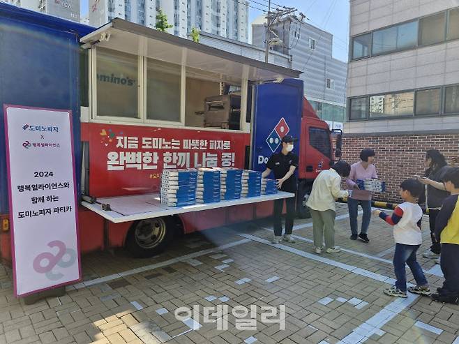 행복얼라이언스가 지난 13일 도미노피자와 함께 피자 나눔 푸드트럭 ‘도미노피자 파티카’를 통해 서울시 동대문구 염광지역아동센터 아이에게 피자를 나눠주고 있다. (사진=행복얼라이언스 제공)