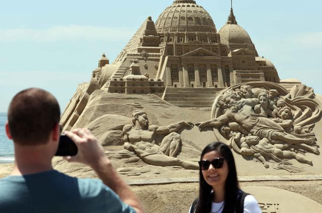 지난 19일 부산 해운대해수욕장을 찾은 외국인 관광객들이 '2024 해운대 모래축제'에 선보일 모래조각 작품 을 배경으로 기념사진을 찍고 있다. 뉴시스