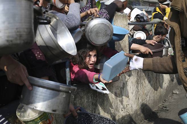 지난 1월9일(현지시간) 가자지구 최남단 도시 라파에서 피란민들이 식량 배급을 받기 위해 그릇을 내밀고 있다. 유엔은 5월21일 이스라엘군의 군사작전과 식량 부족으로 라파에서 배급이 전면 중단됐다고 밝혔다. AP연합뉴스