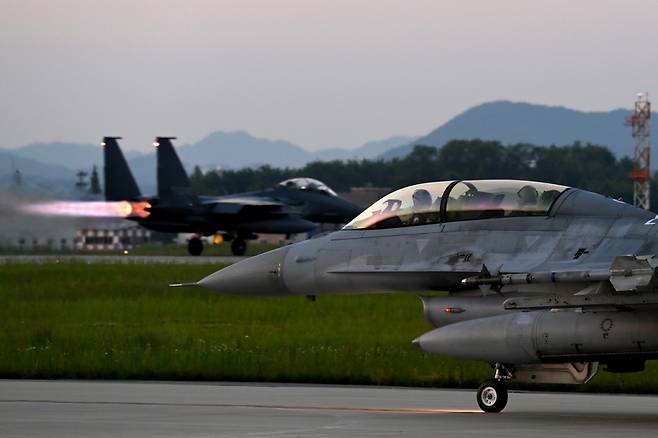 사진은 야간 출격을 위해 지상에서 이동하고 있는 F-16과 그 뒤로 이륙하기 위해 활주 중인 F-15K. / 사진=공군