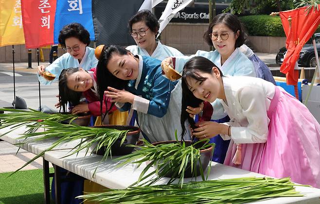 22일 서울 청계광장에서 전국단오제연합이 '단오, 단 하나가 되다'라는 주제로 합동 홍보 행사가 진행된 가운데 참가자들이 참포머리감기 체험을 하고 있다.
