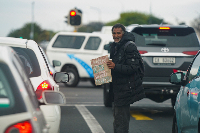 남아공의 한 노숙자가 지난 21일 신호 대기 중인 운전자들에게 구걸하고 있는 모습.   AFP 로이터 연합뉴스