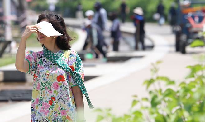 초여름 날씨를 보인 22일 서울 영등포구 여의도한강공원에서 한 시민이 종이로 햇빛을 가리며 걷고 있다. 연합뉴스