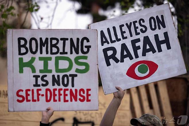 팔레스타인을 옹호하는 시위대원들이 7일 '어린이를 향한 공습은 자위 행위가 아니다' '모든 눈은 라파로 향한다'는 피켓을 들고 로스앤젤레스 캘리포니아 주립대(칼스테이트) 앞에서 이스라엘군의 가자 라파시 진입에 반대하는 시위를 벌이고 있다. 2024.05.08 ⓒ AFP=뉴스1 ⓒ News1 정지윤기자