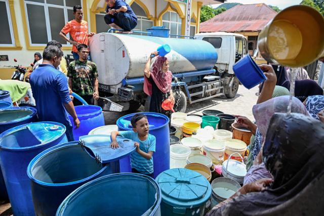 극한 폭염과 가뭄이 덮친 인도네시아 수마트라섬 아체특별자치주에서 지난 12일 시민들이 배급받은 물로 더위를 식히고 있다. 아체=AFP 연합뉴스