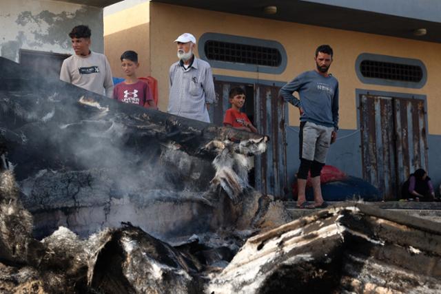 팔레스타인 피란민들이 지난 22일 가자지구 최남단 도시 라파에서 이스라엘군 공습으로 잿더미가 된 고기잡이배를 바라보고 있다. 라파=AFP 연합뉴스