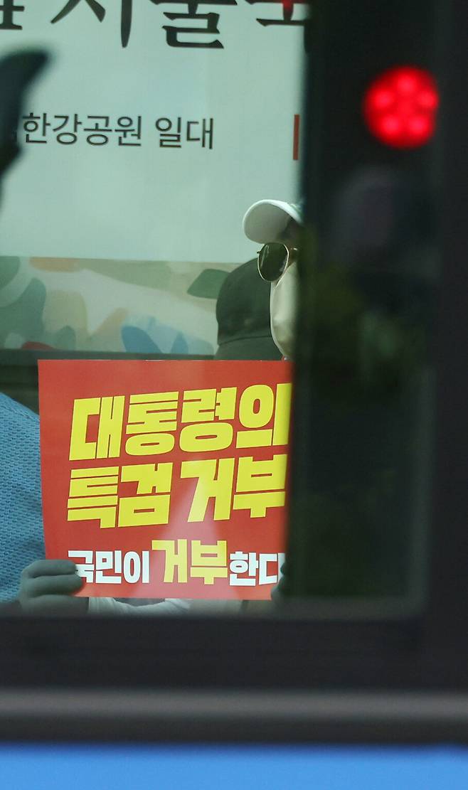 한 시민이 손팻말을 들고 있는 모습이 버스 너머로 보이고 있다. 김혜윤 기자