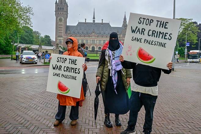 팔레스타인 지지 시위대가 지난 24일(현지시간) 네덜란드 헤이그 국제사법재판소(ICJ) 앞에서 이스라엘의 가자지구 공격 중단을 촉구하고 있다. 수박은 팔레스타인 국기에 담긴 빨간색, 녹색, 검은색, 흰색이 모두 포함돼 있어 팔레스타인 연대의 상징으로 쓰이고 있다.       AFP연합뉴스