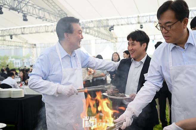 ▲윤석열 대통령이 24일 용산 대통령실 잔디마당에서 열린 '대통령의 저녁 초대' 만찬 행사에서 고기를 굽고 있는 모습. ⓒ대통령실