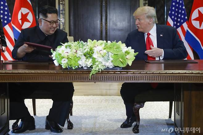 【싱가포르=AP/뉴시스】도널드 트럼프 미국 대통령과 김정은 북한 국무위원장이 12일 싱가포르 센토사 섬 내 카펠라 호텔에서 합의문에 서명한 후 웃고 있다 /사진=뉴시스