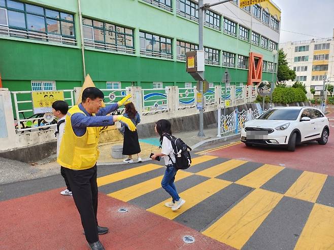 창원 용남초등학교에서 배움터지킴이로 근무하는 한길수씨가 등교하는 아이들의 안전을 위해 수신호를 보내고 있다.