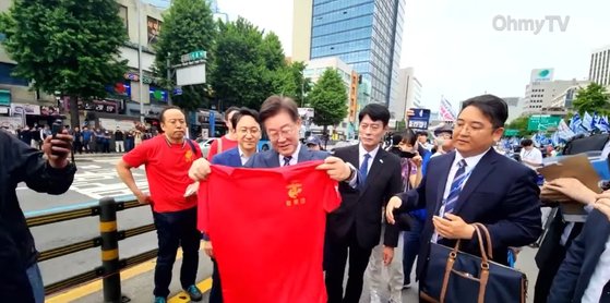 이재명 더불어민주당 대표가 25일 서울역 일대에서 열린 채상병 특검법 통과 촉구 집회에서 해병대 전우회 회원에게 붉은 티셔츠를 선물 받았다. 사진 유튜브 오마이tv 캡쳐