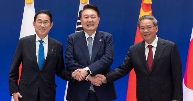 President Yoon Suk-yeol holds hands with Japanese Prime Minister Fumio Kishida (L) and Chinese Premier Li Keqiang (R) before the ninth trilateral summit between China, Japan and South Korea at the presidential Blue House on Sunday. By Kim Chang-gil